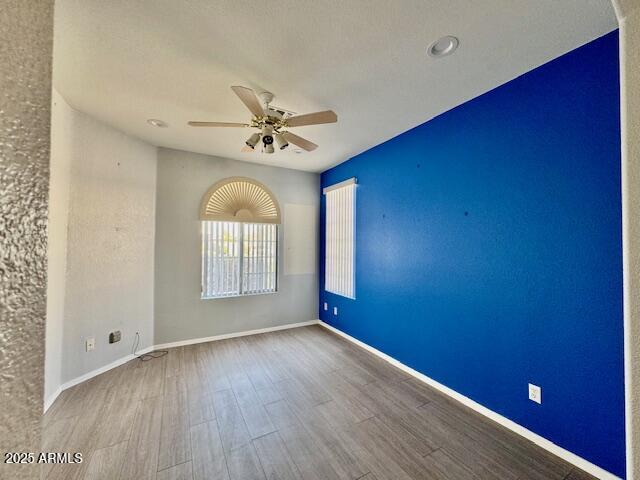 empty room with a ceiling fan, baseboards, and wood finished floors