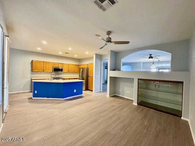 kitchen with baseboards, visible vents, light wood-style flooring, stainless steel appliances, and light countertops