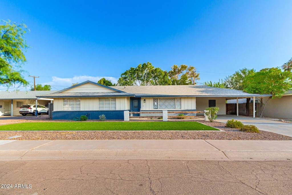 ranch-style home featuring a front lawn and a carport