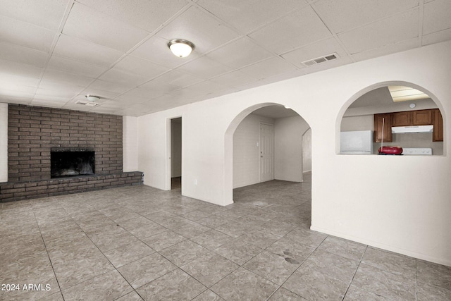 unfurnished living room with light tile patterned flooring, a fireplace, and a paneled ceiling