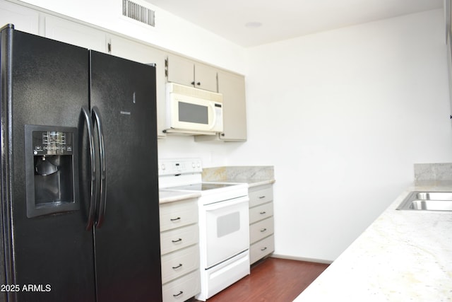 kitchen with dark hardwood / wood-style flooring, white appliances, and cream cabinetry