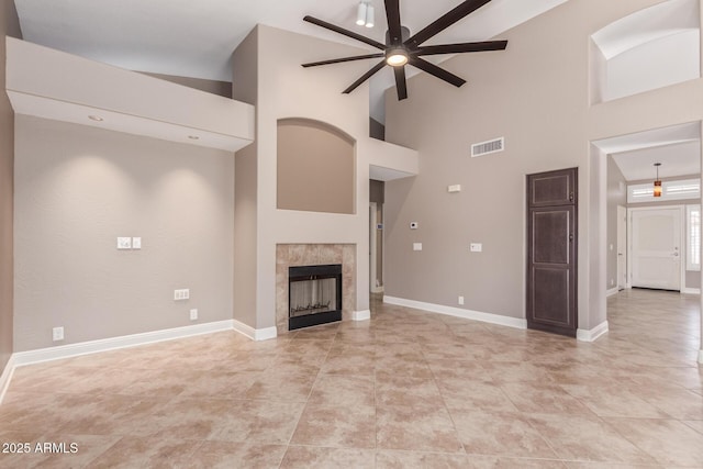 unfurnished living room featuring visible vents, baseboards, ceiling fan, a fireplace, and high vaulted ceiling