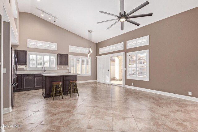 kitchen featuring high vaulted ceiling, light countertops, dark brown cabinets, and ceiling fan