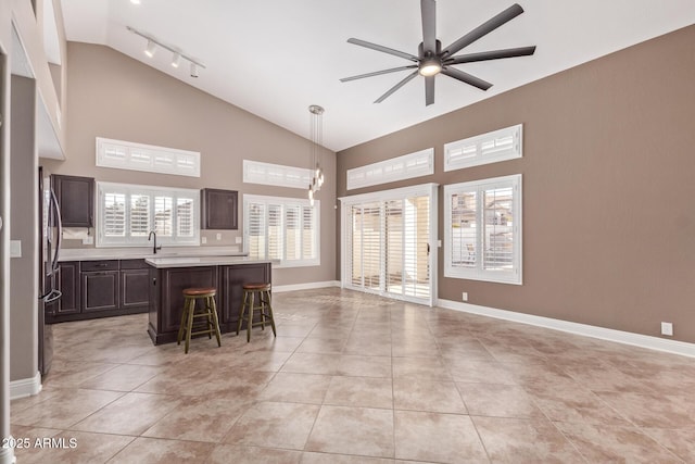 interior space with dark brown cabinetry, a ceiling fan, a breakfast bar, light tile patterned flooring, and light countertops