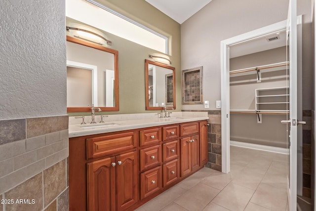 full bathroom with double vanity, a sink, tile patterned flooring, and tile walls