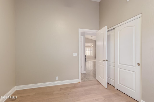 unfurnished bedroom with a closet, baseboards, and light wood-style floors