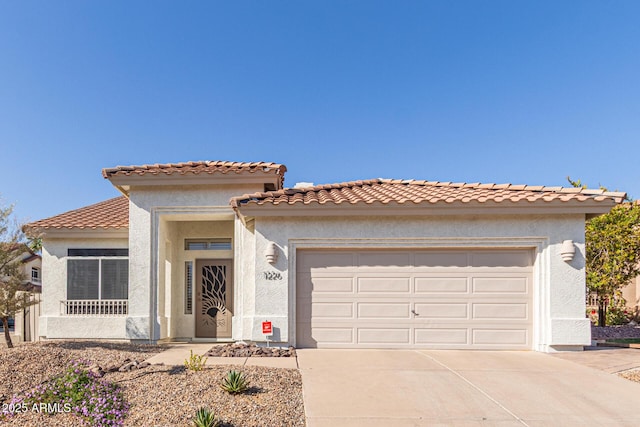 mediterranean / spanish-style home with concrete driveway, stucco siding, a tile roof, and a garage