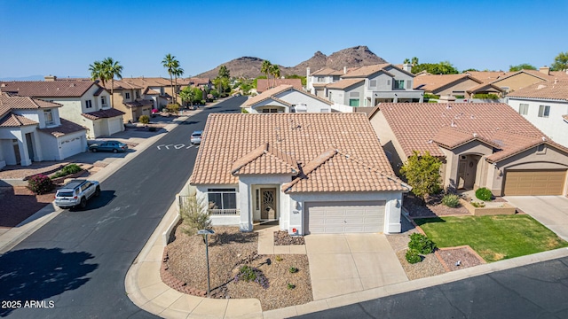 view of front of property with a residential view, stucco siding, driveway, an attached garage, and a tile roof