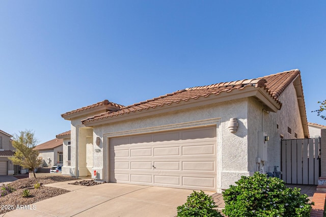 view of front of house with concrete driveway, stucco siding, a tile roof, and a garage