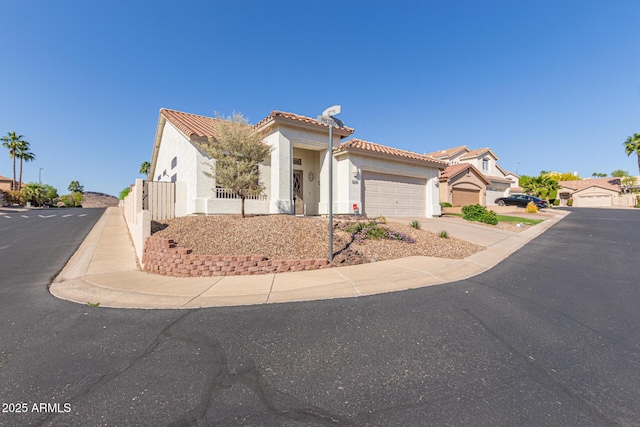 mediterranean / spanish home with a tiled roof, a garage, stucco siding, and driveway
