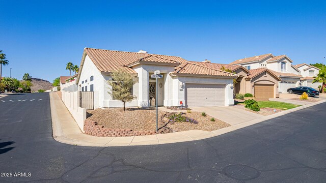 mediterranean / spanish-style house with concrete driveway, a tile roof, a garage, and stucco siding