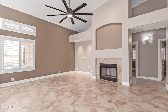 unfurnished living room with light tile patterned floors, baseboards, a ceiling fan, a fireplace, and high vaulted ceiling