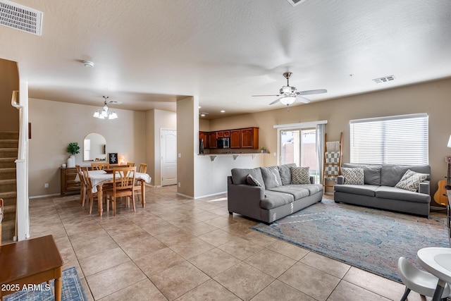 living room with stairs, visible vents, and light tile patterned flooring