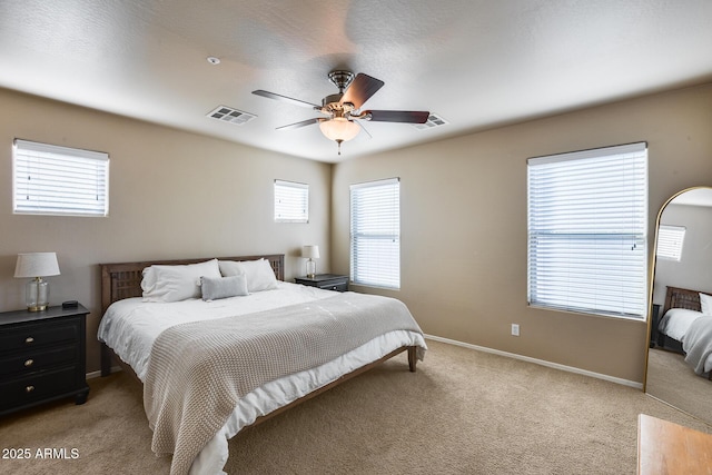 bedroom featuring a ceiling fan, light colored carpet, visible vents, and baseboards