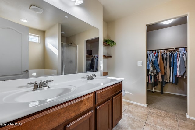 bathroom featuring tile patterned flooring, a shower stall, a walk in closet, and a sink