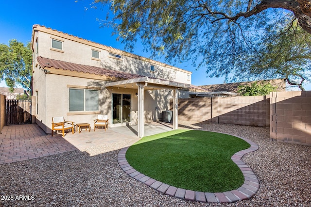 back of property with a fenced backyard, a tiled roof, a gate, stucco siding, and a patio area