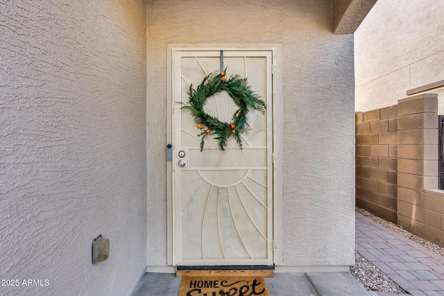 property entrance featuring fence and stucco siding