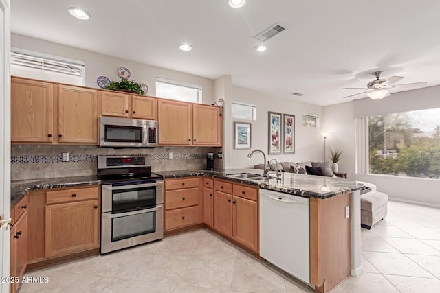 kitchen with visible vents, a sink, tasteful backsplash, appliances with stainless steel finishes, and a peninsula