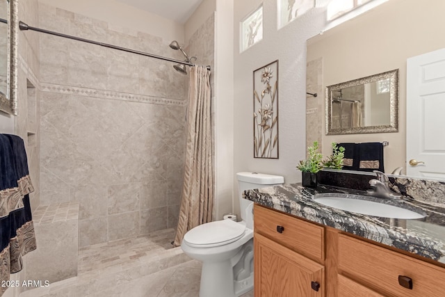 bathroom featuring vanity, toilet, and a tile shower