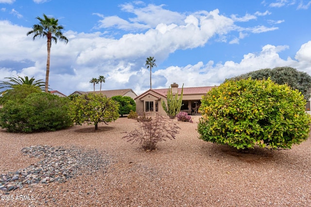 back of property with a tile roof, stucco siding, and a chimney