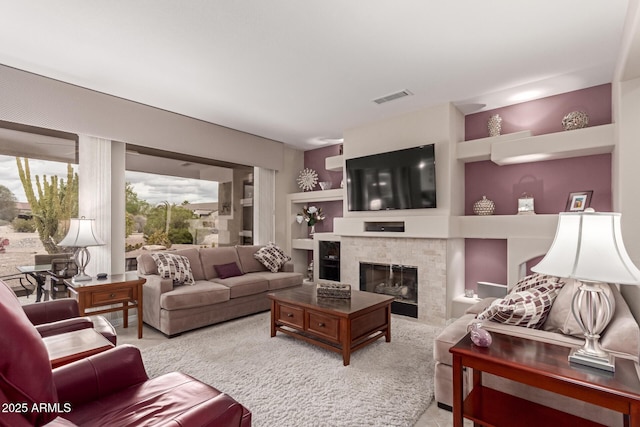 carpeted living room with built in features, visible vents, and a glass covered fireplace