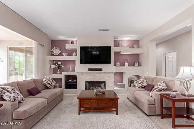 living room with visible vents, built in shelves, and a fireplace