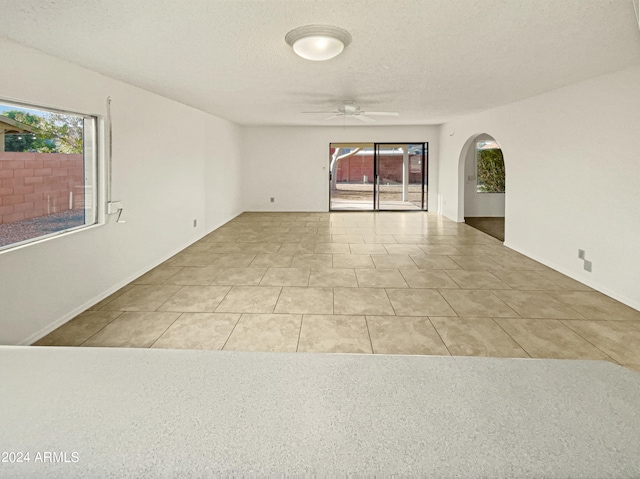 empty room with ceiling fan, light tile patterned flooring, and a wealth of natural light