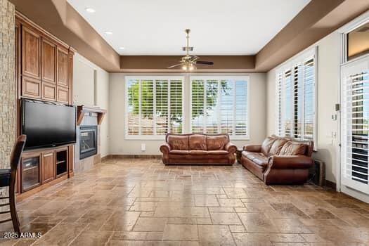 11986 N 134th Pl, Scottsdale, AZ 85259 - living area featuring stone tile flooring, a ceiling fan, baseboards, a glass covered fireplace, and recessed lighting