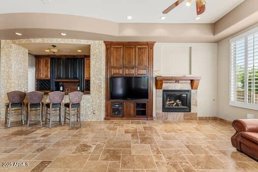 11986 N 134th Pl, Scottsdale, AZ 85259 - living area with ceiling fan, stone finish floors, a glass covered fireplace, and arched walkways