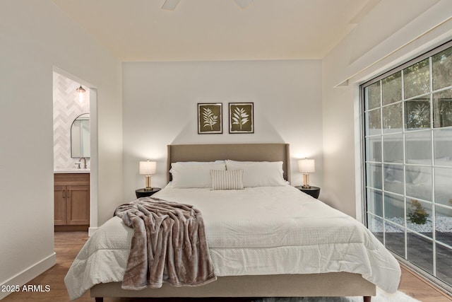 7710 E Gainey Ranch Rd Unit 142, Scottsdale, AZ 85258 - bedroom with wood finished floors, access to exterior, ensuite bathroom, a sink, and baseboards