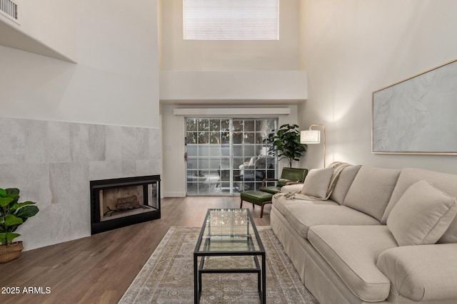 7710 E Gainey Ranch Rd Unit 142, Scottsdale, AZ 85258 - living room with wood finished floors, a tiled fireplace, a towering ceiling, and plenty of natural light