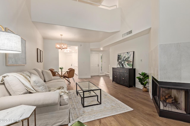 7710 E Gainey Ranch Rd Unit 142, Scottsdale, AZ 85258 - living room with wood finished floors, a chandelier, a tiled fireplace, baseboards, and a high ceiling