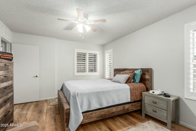 bedroom featuring ceiling fan, light wood-type flooring, and a textured ceiling