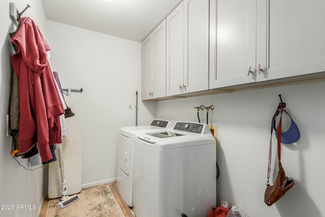 clothes washing area with cabinets and washing machine and dryer