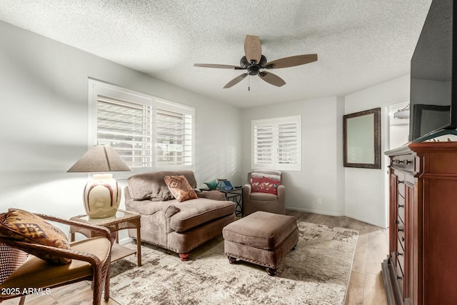 sitting room with ceiling fan, a textured ceiling, and light wood-type flooring