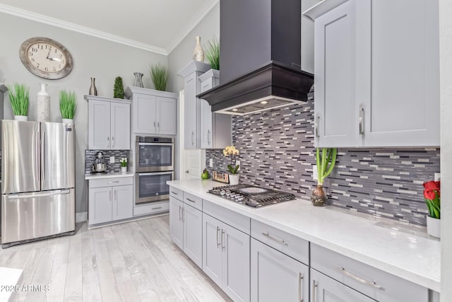 kitchen with premium range hood, crown molding, appliances with stainless steel finishes, light hardwood / wood-style floors, and backsplash