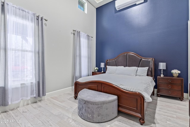 bedroom featuring light hardwood / wood-style flooring and an AC wall unit