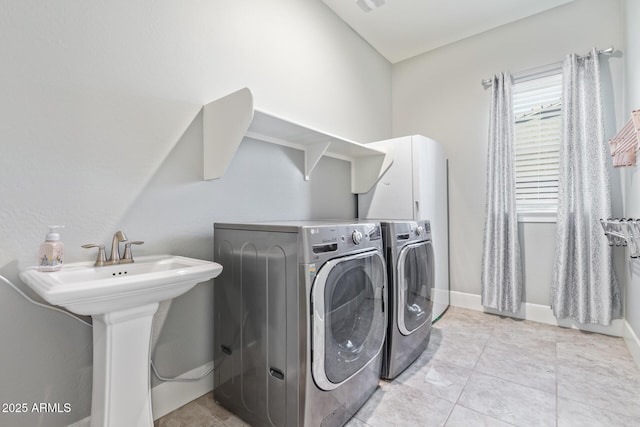 laundry area with sink, light tile patterned floors, and washer and clothes dryer