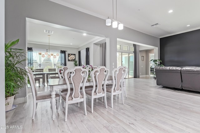 dining area featuring crown molding, a chandelier, and light hardwood / wood-style floors