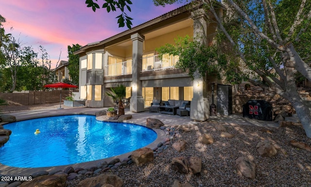 pool at dusk with an outdoor living space and a patio area