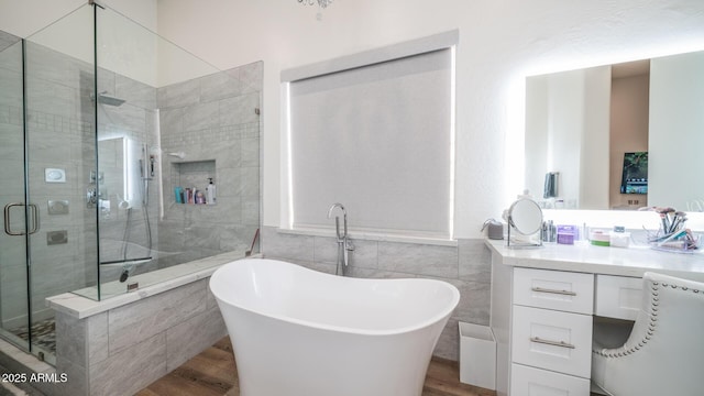 bathroom with shower with separate bathtub, wood-type flooring, tile walls, and vanity