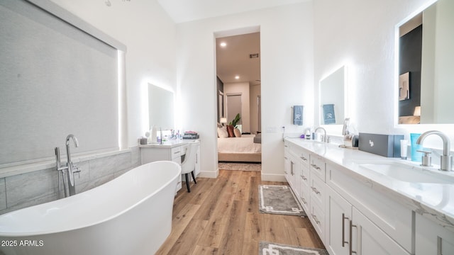 bathroom with hardwood / wood-style flooring, vanity, and a tub to relax in