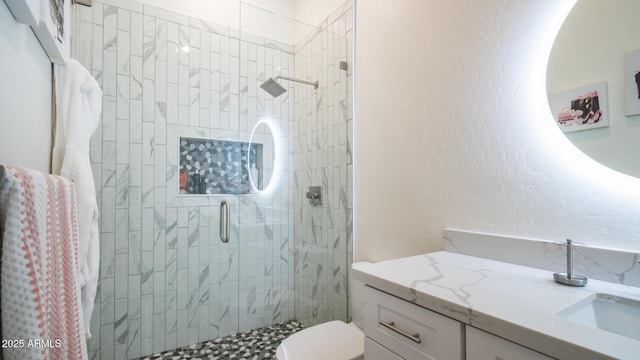 bathroom featuring a shower with door, vanity, and toilet