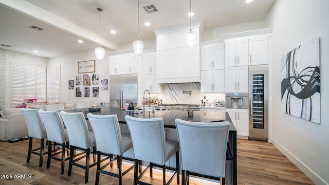 kitchen with hanging light fixtures, stainless steel built in refrigerator, and white cabinets