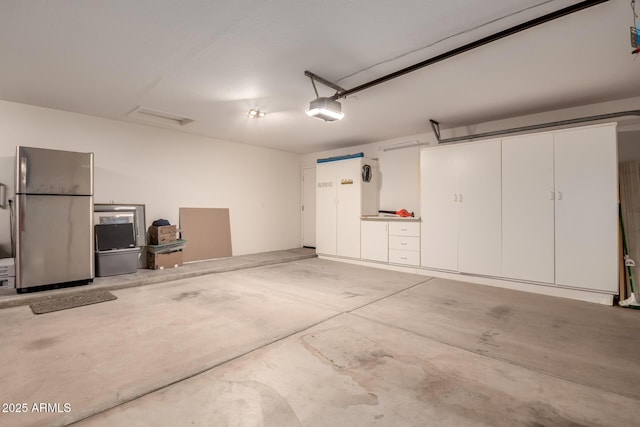 garage with stainless steel fridge and a garage door opener