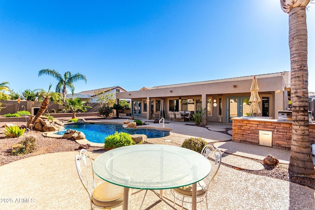 view of swimming pool with an outdoor kitchen, a patio, and french doors