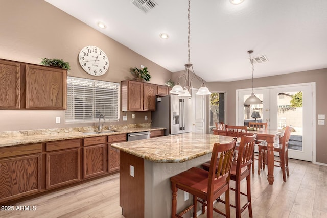 kitchen featuring a center island, french doors, vaulted ceiling, a kitchen bar, and appliances with stainless steel finishes