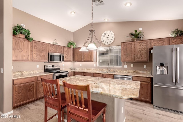 kitchen featuring light hardwood / wood-style floors, a kitchen island, hanging light fixtures, and appliances with stainless steel finishes