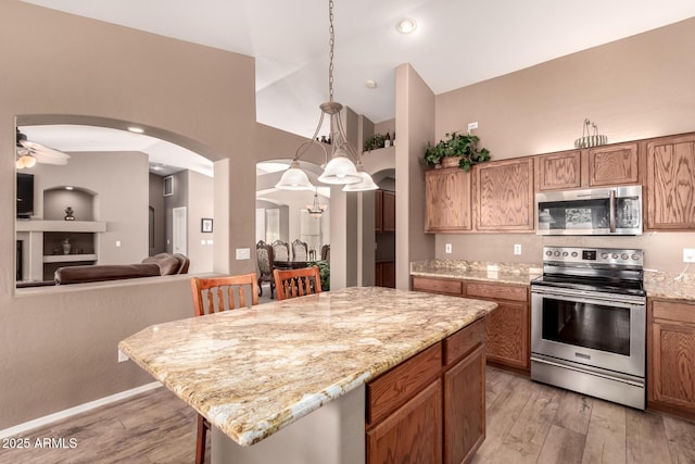 kitchen featuring a breakfast bar, a center island, light hardwood / wood-style flooring, appliances with stainless steel finishes, and decorative light fixtures