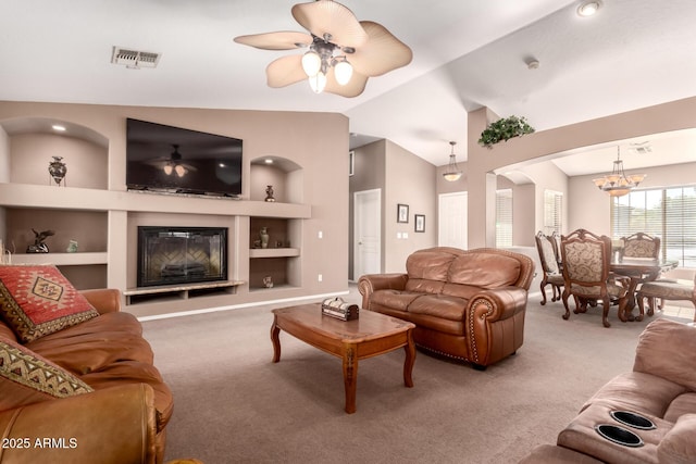 carpeted living room featuring ceiling fan with notable chandelier, built in features, and lofted ceiling